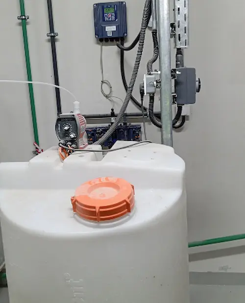 Complete chlorine dosing system installed on a drinking water supply line featuring a digital controller, dosing pump, and sodium hypochlorite chemical tank.