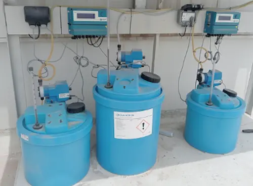 Operational cooling tower chemical dosing system featuring an active digital controller, metering pumps, and filled chemical tanks.