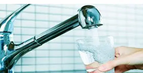 Fresh drinking water pouring from a clean stainless steel faucet.