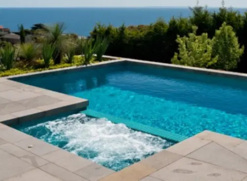 In-ground concrete swimming pool with blue mosaic tiles and a built-in spa