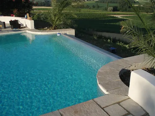 Outdoor swimming pool with clear blue water and green grass