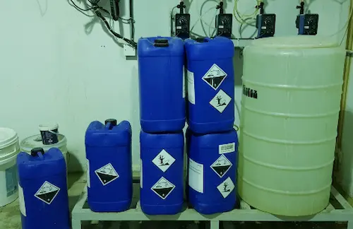 Water treatment chemicals placed securely under dosing pumps for automated chemical injection inside a treatment facility
